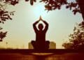 Silhouette of a person practicing yoga outdoors during sunrise, creating a calming atmosphere.