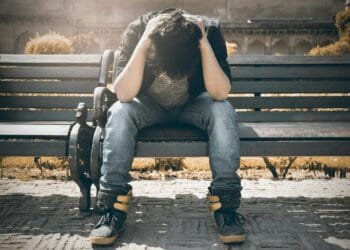 Man sitting alone on a bench in Agra, displaying signs of stress and loneliness.