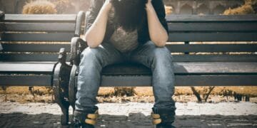 Man sitting alone on a bench in Agra, displaying signs of stress and loneliness.