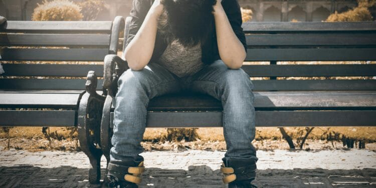 Man sitting alone on a bench in Agra, displaying signs of stress and loneliness.