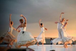 Elegant ballerinas performing a captivating dance at sunset outdoors.