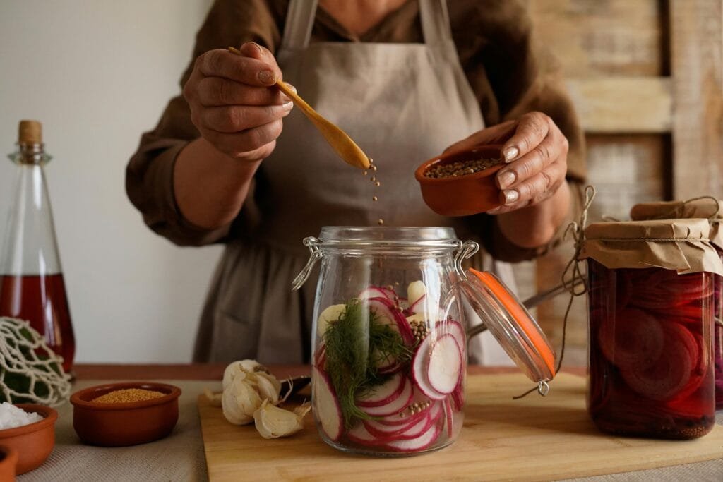 Hands preparing pickled vegetables in a jar, capturing a rustic and organic lifestyle.