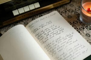 An open journal with handwritten notes beside a candle and vintage radio, evoking nostalgia.