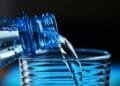 Close-up of sparkling water being poured from a bottle into a glass with bubbles visible.