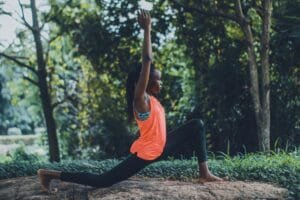 Woman practicing yoga outdoors in a serene forest setting, embracing fitness and tranquility.