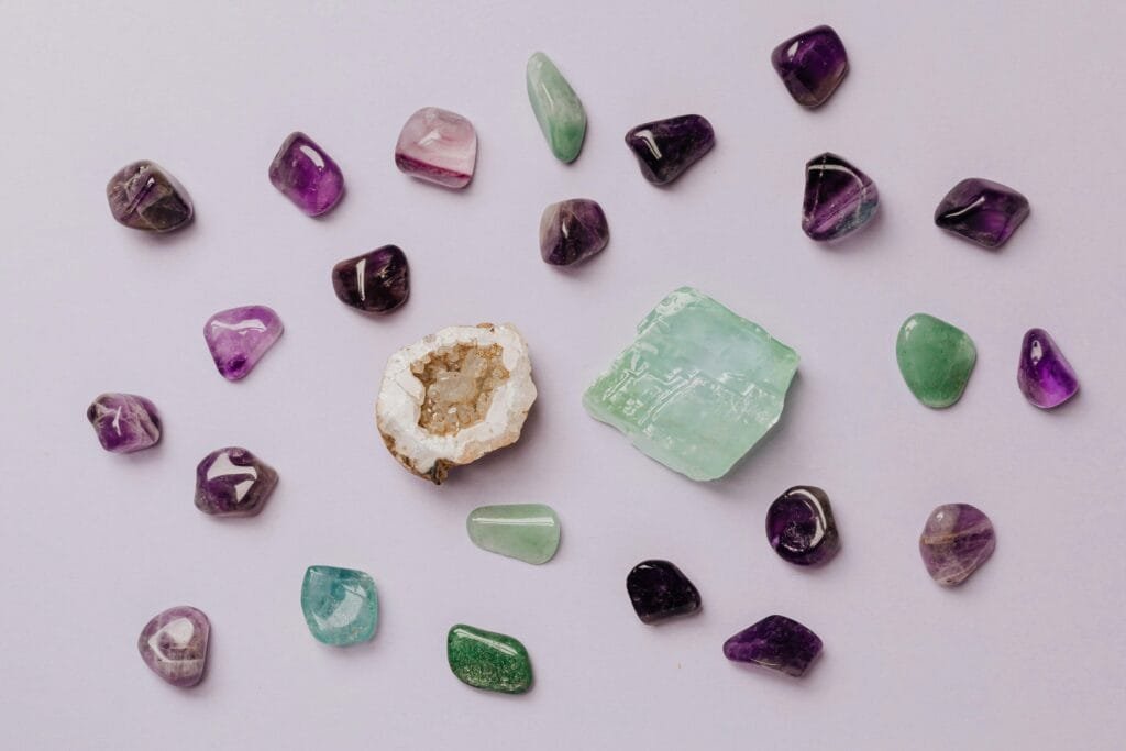 Flat lay of assorted polished gemstones including amethyst and jade on a light background.