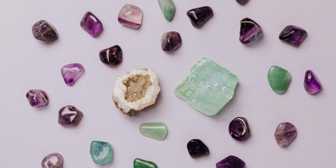 Flat lay of assorted polished gemstones including amethyst and jade on a light background.