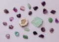 Flat lay of assorted polished gemstones including amethyst and jade on a light background.