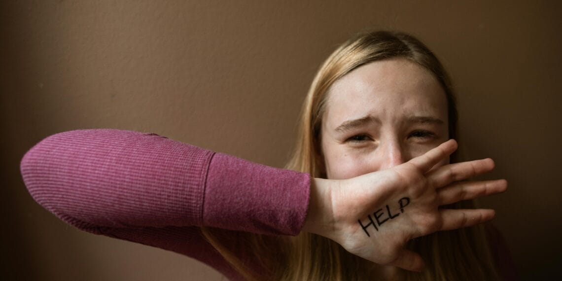 A woman with 'HELP' written on her palm. Emotion and assistance theme.