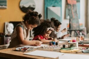 Three young girls expressing creativity in a vibrant art studio environment.