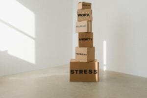 Cardboard boxes stacked in an empty room, symbolizing stress and anxiety with labeled problems.