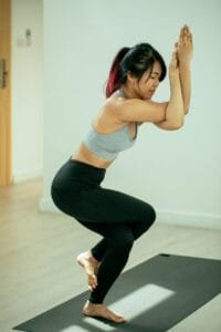 Focused young woman performing the eagle pose in a serene indoor setting for balance and wellness.