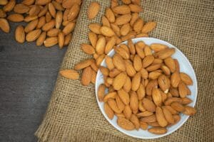 Top view of almonds in a white bowl on a burlap surface, highlighting healthy snacking.