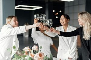 Women celebrating indoors with a toast, clinking wine glasses, joyful and smiling.