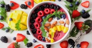 A vibrant, healthy fruit smoothie bowl topped with fresh berries, mango, and almonds.
