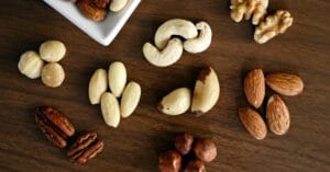 Close-up of various nuts on a wooden table, showcasing healthy snacking options.