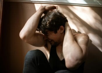 A man experiencing emotional distress in a dimly lit room, symbolizing struggle and mental health.