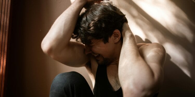 A man experiencing emotional distress in a dimly lit room, symbolizing struggle and mental health.