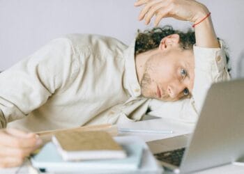 A tired Caucasian man at a desk, showing signs of exhaustion and stress, exemplifying workplace burnout.