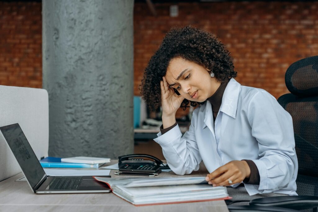How to Recover From Burnout Without Quitting Your Career Businesswoman experiencing fatigue while working on financial paperwork at her desk.