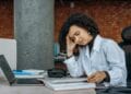 How to Recover From Burnout Without Quitting Your Career Businesswoman experiencing fatigue while working on financial paperwork at her desk.