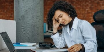How to Recover From Burnout Without Quitting Your Career Businesswoman experiencing fatigue while working on financial paperwork at her desk.